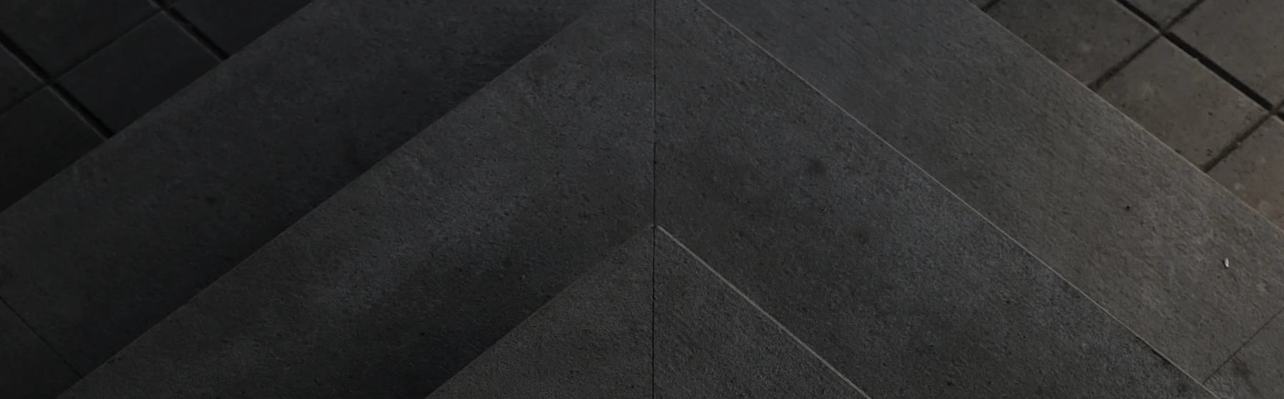 Cast concrete steps meeting at a ridge, lit from one side.