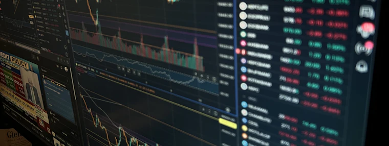A trading terminal showing price charts and a quote board in low light.